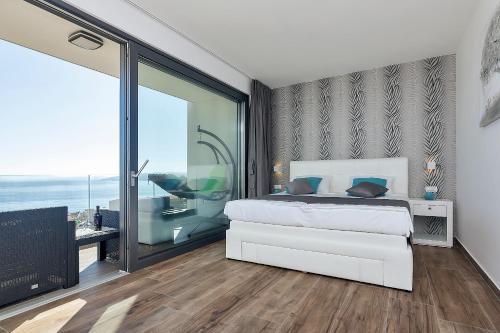 ein Schlafzimmer mit einem weißen Bett und einem großen Fenster in der Unterkunft Villa Selina - Nera in Makarska