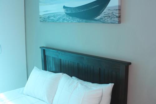 1 cama con cabecero de madera y una foto encima en Ocean Sunset, en Seaview