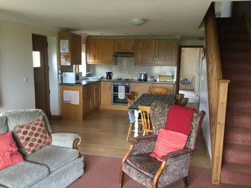 a living room with two chairs and a kitchen at Lazy Daisys in Langsett