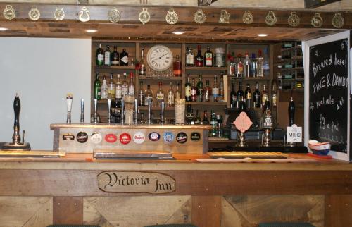 un bar con reloj y botellas de alcohol en Victoria Inn Brewhouse B&B en Roch