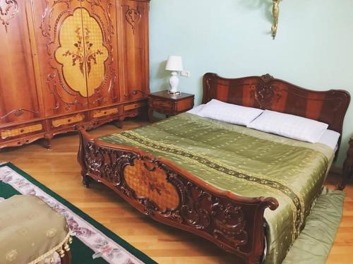 a bedroom with a bed with a wooden headboard at Apartament Balakhvani in Kutaisi