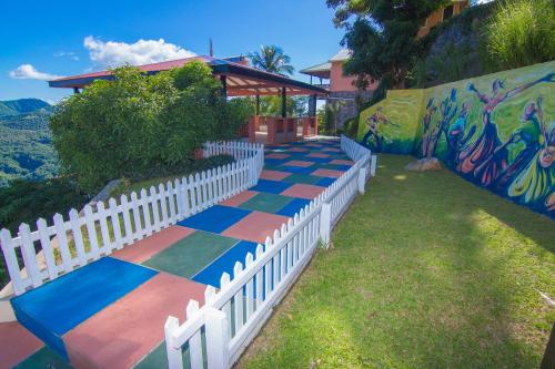 a white picket fence and a colorful sidewalk at Samfi Gardens in Soufrière