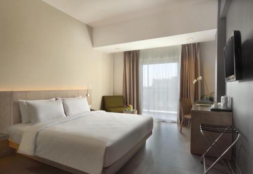 a bedroom with a large white bed and a window at Hotel Santika Siligita Nusa Dua in Nusa Dua