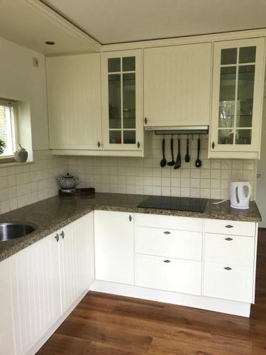 a kitchen with white cabinets and a sink at Vakantiewoning Tjiftjaf in "Het Fonteinbos" in Oudemirdum