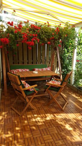 a wooden table and chairs on a patio with red flowers at Exklusives Haus mit Garten in Hannover