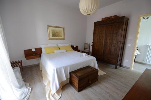 ブラにあるB&B Il Ficoの白いベッドと木製キャビネット付きのベッドルーム1室が備わります。