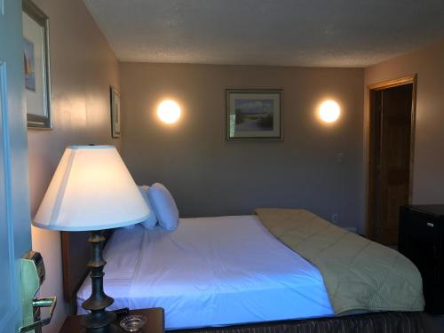 een slaapkamer met een bed met een lamp en een lampaal bij Capri Motel in North Dartmouth