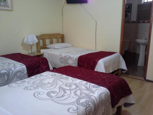 a hotel room with three beds in a room at Apart & Hostal ManuAlé in Tacna