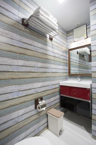 a bathroom with a wooden accent wall with a sink and a mirror at Night Bazaar Inn in Chiang Mai