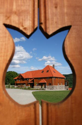 a building with a red roof viewed through a fence at Honor Villa in Izvoare