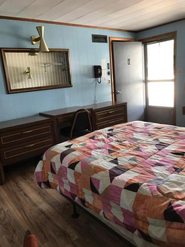 a bedroom with a bed and a desk and a mirror at Melody Motor Lodge in Connellsville