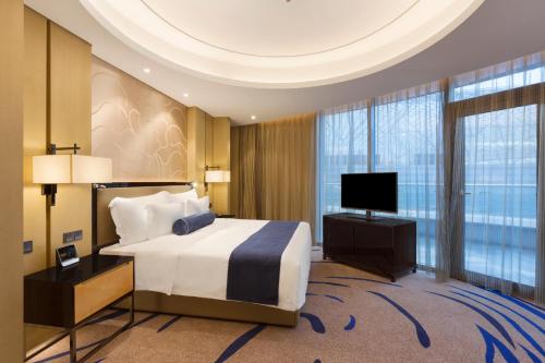 a hotel room with a bed and a television at Wyndham Chongqing Yuelai in Chongqing