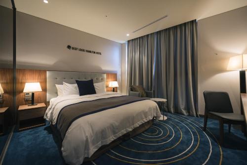 a hotel room with a large bed and a desk at Best Louis Hamilton Hotel Changwon in Changwon
