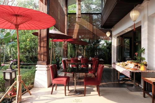 een restaurant met rode stoelen, tafels en parasols bij Risasinee Spa & Resort in Nan