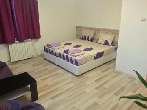 a bedroom with a bed with purple pillows on it at Guest House Bedrock in Belogradchik