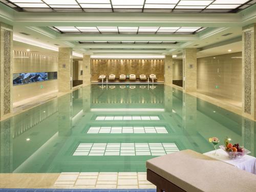 a swimming pool with a table and chairs in it at Kunshan Jinling Hotel in Kunshan