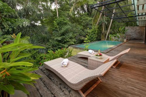 a patio with a table and chairs next to a swimming pool at Sativa Villas Ubud with Private Pool in Ubud