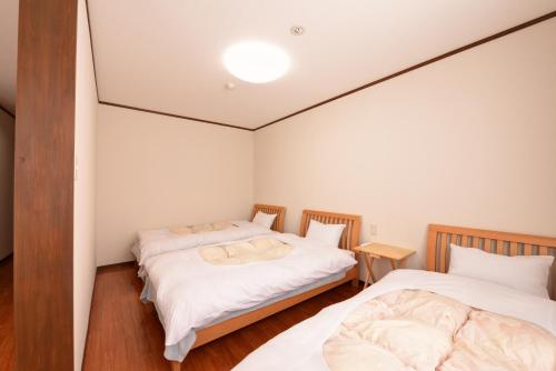 two beds in a room with white walls at Lodge B&W in Minami Uonuma