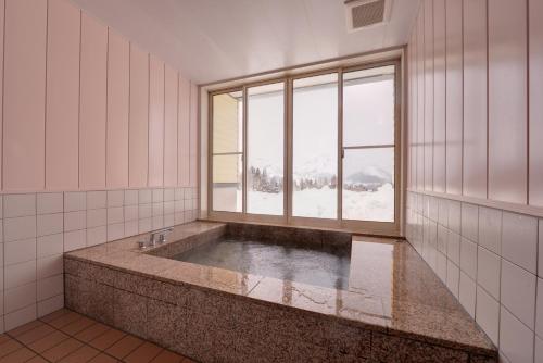 Lodge B&W في Minami Uonuma: حوض استحمام في غرفة مع نافذة