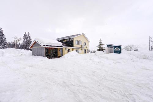 a house is covered in snow at Lodge B&W in Minami Uonuma