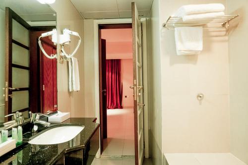 a bathroom with a sink and a mirror at La Rosa Hotel Oman in Muscat