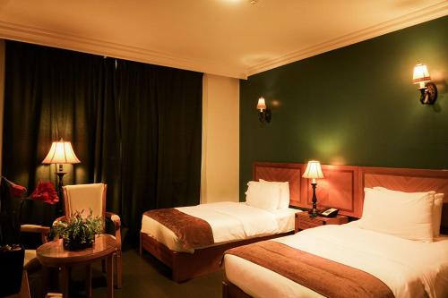 a hotel room with two beds and a green wall at La Rosa Hotel Oman in Muscat