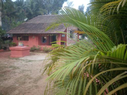 a red house with a palm tree in front of it at Samarth Atc-Beach Home Stay in Ratnagiri