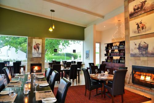 un restaurante con mesas y sillas y una chimenea en Val Du Charron Wine & Leisure Estate, en Wellington