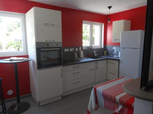 a kitchen with white cabinets and red walls at Le Studio in Saint-Aignan-Grand-Lieu