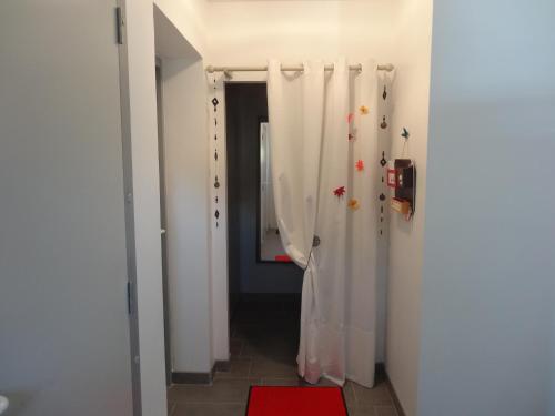 Le Studio في Saint-Aignan-Grand-Lieu: حمام مع ستائر دش بيضاء وسجادة حمراء