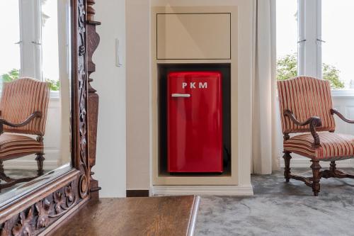 a red refrigerator in a room with two chairs at Hotel Villa Grunewald in Bad Nauheim