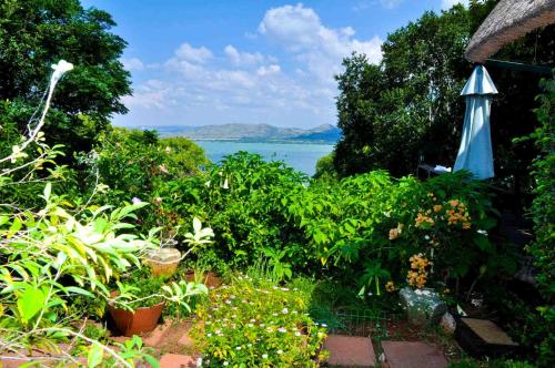 a garden with an umbrella and a view of the water at Bali at Scenic Haven Lodge in Hartbeespoort in Hartbeespoort