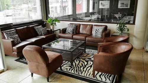 a living room with couches and a table and chairs at H&ocirc;tel Notre Dame de la Sarte in Lourdes