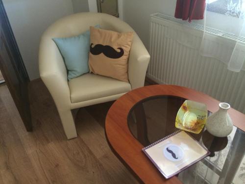 a chair with a moustache pillow and a table at Bajusz Vendégház in Tornyosnémeti
