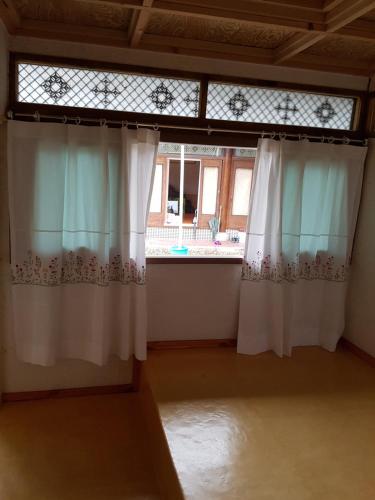 a room with white curtains and a window at The Hanok in Jeonju