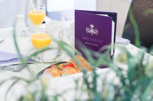 a table with a plate of food and glasses of orange juice at Beachlands Hotel in Weston-super-Mare