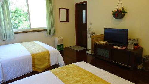 a bedroom with two beds and a flat screen tv at Emoonten Homestay in Sanzhi