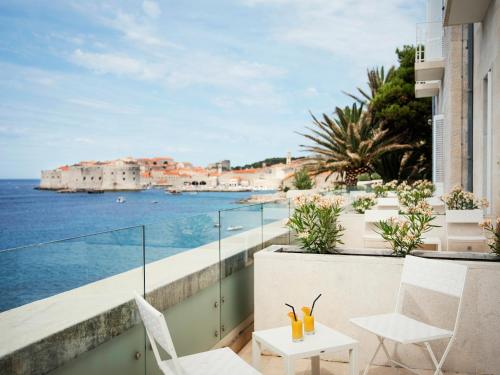 a balcony with chairs and a view of the ocean at Hotel Excelsior in Dubrovnik
