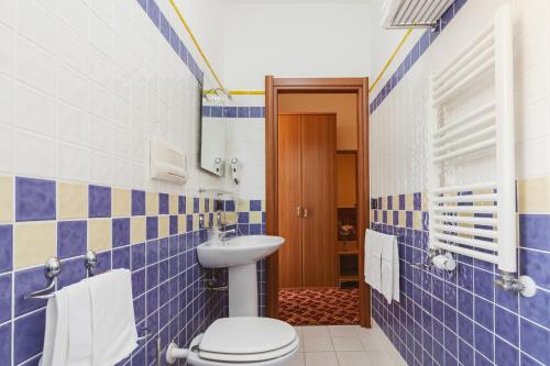a blue tiled bathroom with a toilet and a sink at Hotel Villa Del Sorriso in Venosa