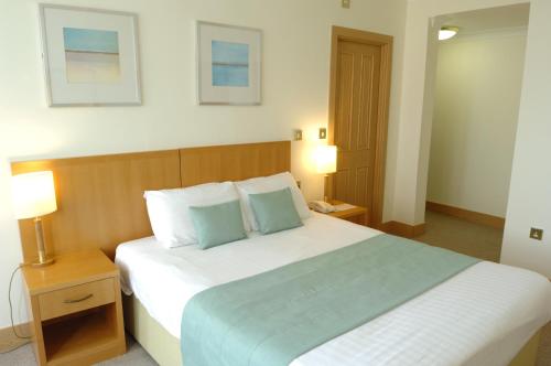 a bedroom with a large white bed with blue pillows at Carousel Hotel in Blackpool