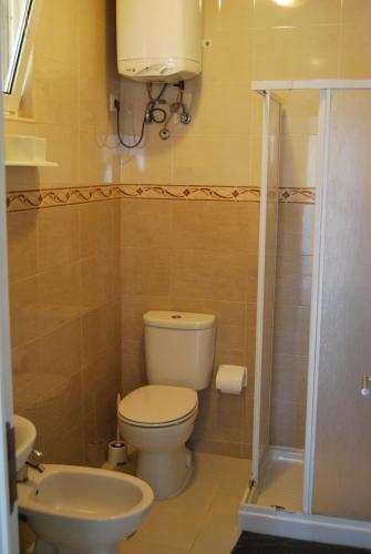 uma casa de banho com um WC, um lavatório e um chuveiro em Apartamentos Costa em Costa da Caparica