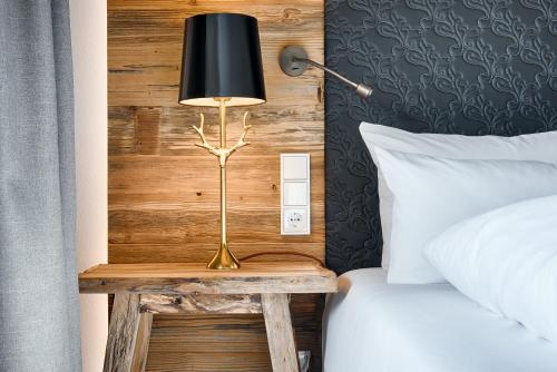 a lamp on a table next to a bed at Obermühle 4*S Boutique Resort in Garmisch-Partenkirchen