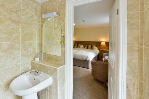 a bathroom with a sink and a shower and a bed at Edenhall Country Hotel in Penrith