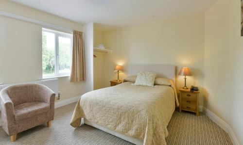 a bedroom with a bed and a chair and a window at Edenhall Country Hotel in Penrith
