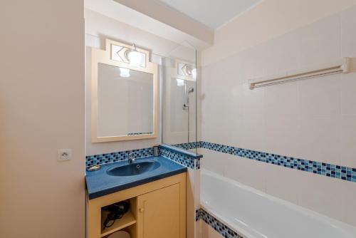 une salle de bain avec un lavabo, un miroir et une baignoire dans l'établissement Residence Heliotel Marine - maeva Home, à Saint-Laurent-du-Var