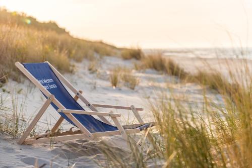 a beach chair sitting in the sand on the beach at Best Western Hotel Jurata in Jurata