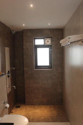 La salle de bains est pourvue d'une douche, d'une fenêtre et d'un lavabo. dans l'établissement Pinto Rosario Square Resort, à Porvorim