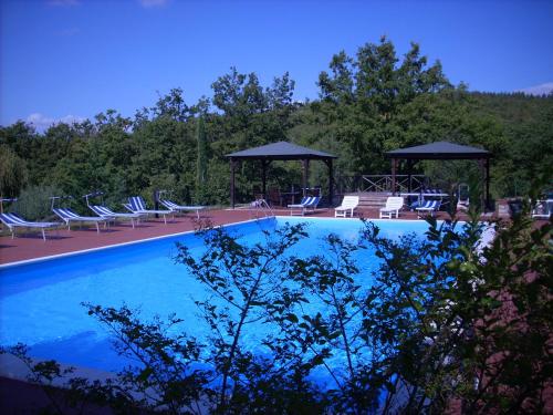 a swimming pool with lounge chairs and a gazebo at Le querce felici in Montegabbione