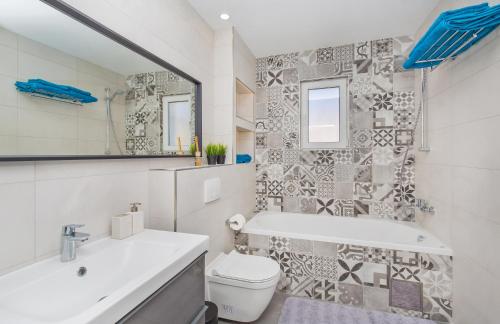 a bathroom with a tub and a toilet and a sink at Apartments Marivo in Mlini