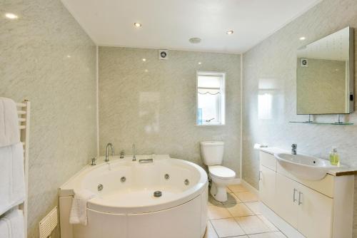 a bathroom with a tub and a toilet and a sink at Edenhall Country Hotel in Penrith